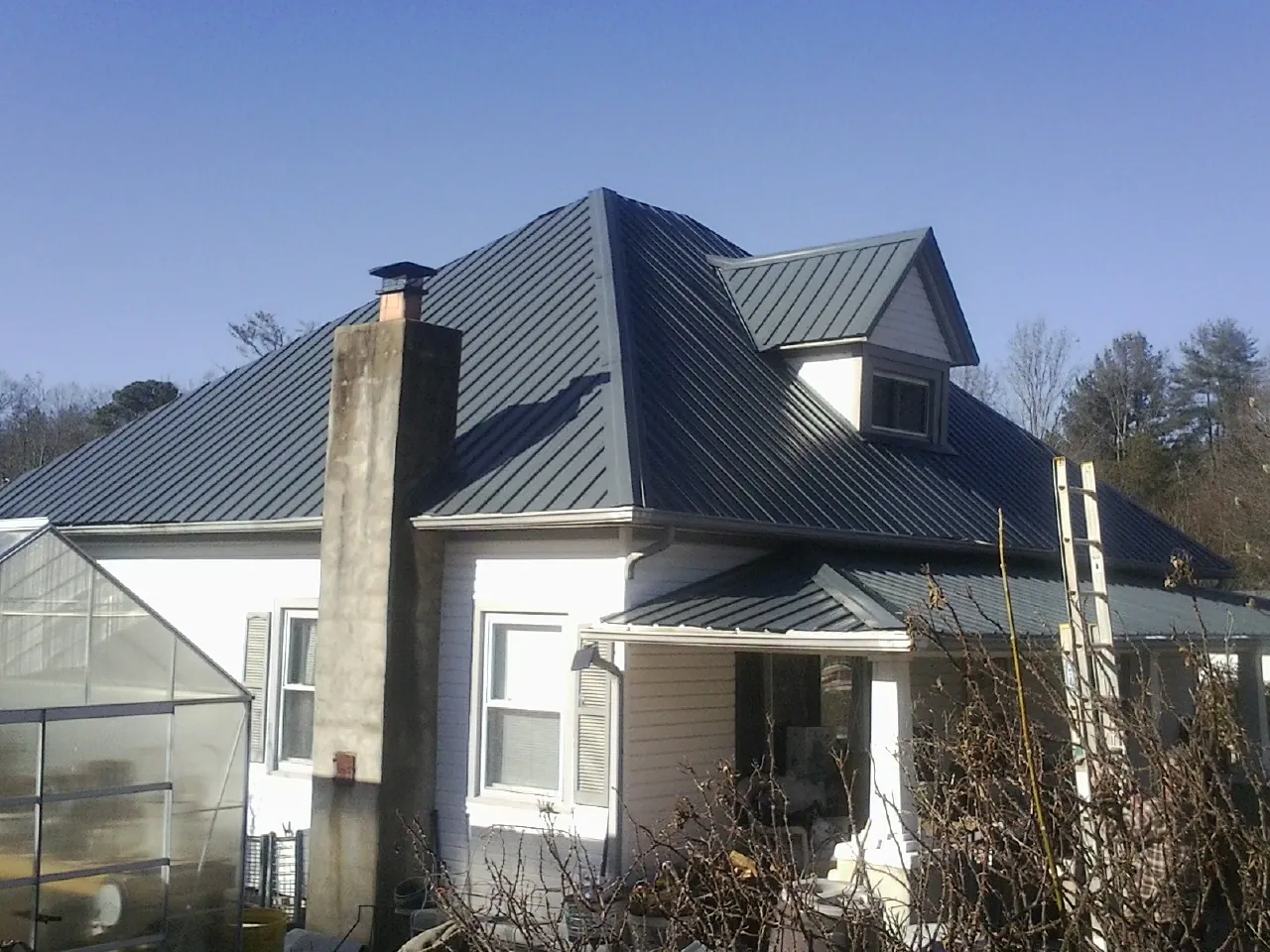 Dark blue standing seam metal roof on a white farmhouse with dormer — Slate & Tile Roof Repair by Roofing Brothers in Perkinsville