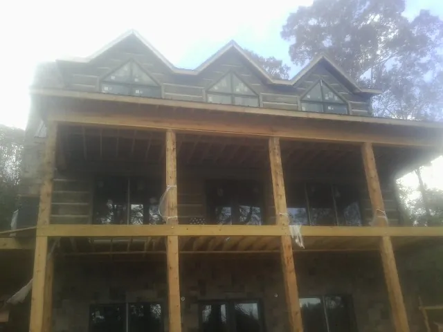 Dormers and porch framing on a large log home under construction — Roof Coating work by our crew in Perkinsville