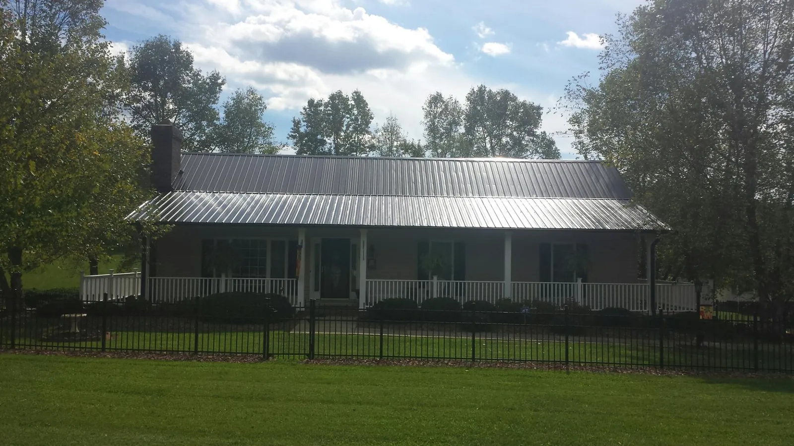 Gray metal roof on a brick ranch with a full width front porch — Gutter Guard Installation work by our crew in Perkinsville
