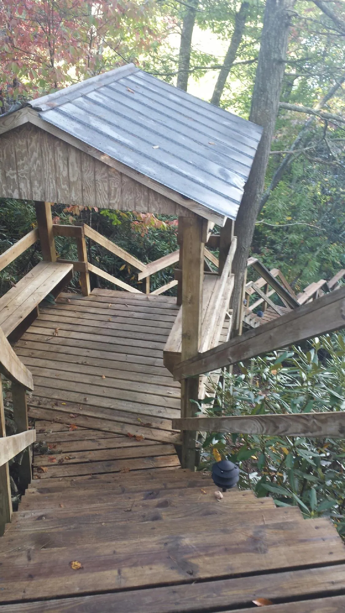 Metal roofed shelter over wooden steps on a wooded walkway — Skylight Repair & Installation work by our crew in Perkinsville