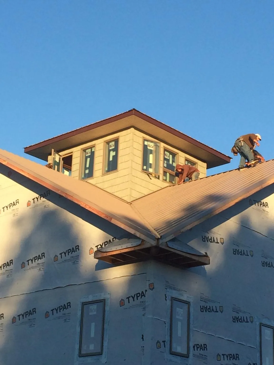Roofers working around a rooftop cupola on a new metal roof at sunset — Roof Waterproofing in Perkinsville by Roofing Brothers